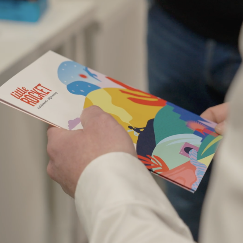 Hands holding Little Rocket brochure